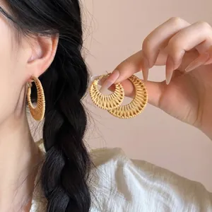 Bohemian style woven raffia drop earrings with golden metal details for a beach vacation look