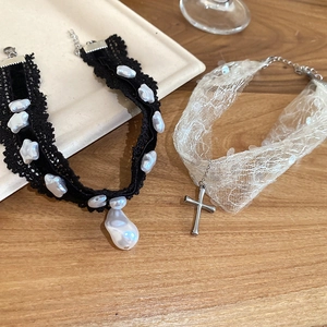Détail de chokers en dentelle avec perles baroques et croix en argent sur bois