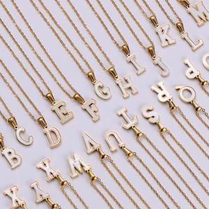 Macro view of gold stainless steel necklaces with white shell initial letter pendants