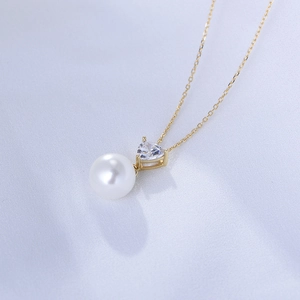 Macro shot of s925 silver heart zircon and white pearl pendant on a gold chain