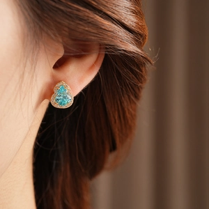 Close-up of hulu-shaped stud earrings with sea-blue gemstone and sparkling cubic zirconia