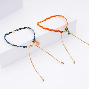 Handmade braided friendship bracelets with gold heart pendants on minimalist display