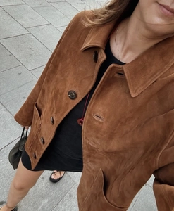 Détail d'une veste en daim marron avec revers et boutons sombres sur un mannequin