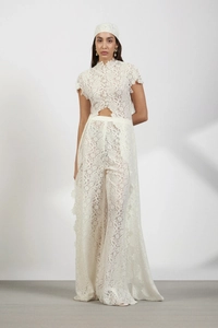 Detailed view of intricate floral lace texture on white wide-leg trousers and matching top