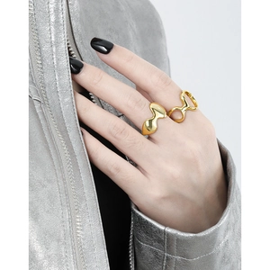 Modern irregular golden rings in liquid metal style worn on model with metallic jacket