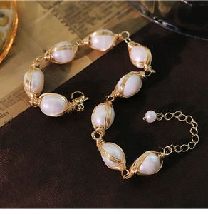 Detailed close-up of handmade baroque pearls bracelet with gold wire wrapping on a retro background