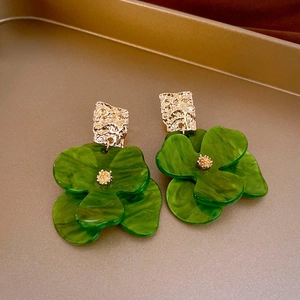 Detailed close-up of amber acrylic flower earrings with golden hammered metal studs