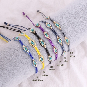 Detailed view of six colorful handmade beaded bracelets on a grey display cylinder