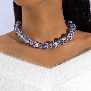Détail de pompons en peluche léopard et de perles métalliques sur le collier