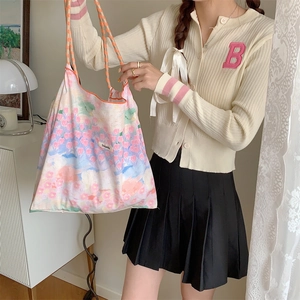 Detailed view of floral tote bag with drawstring and woven straps on model in casual setting