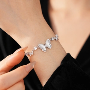 Detail view of silver butterfly bracelet with white resin and zircon on model's wrist