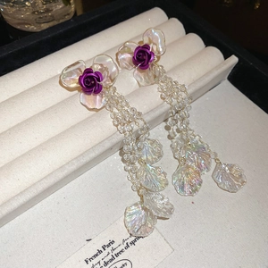Detail of long tassel earrings featuring purple metal roses and iridescent petals