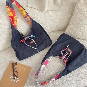 Close-up of denim tote bag featuring colorful patchwork straps and a leather logo label