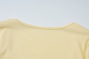 Dettaglio della maglia a coste giallo chiaro con scollatura curva e trama verticale