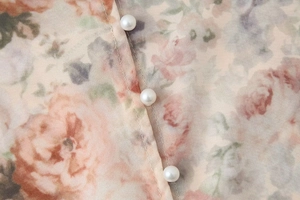 Gros plan détaillé d'une blouse en mousseline fleurie avec boutons de perles et couture