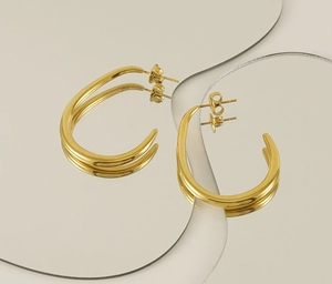 Detailed view of 18K gold-plated U-shaped twist earrings on a reflective studio background
