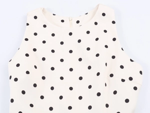 Detailed view of beige polka dot sleeveless top with back zipper and crew neckline