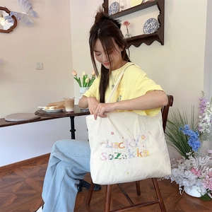 Gros plan sur la broderie colorée Lucky Sozakka sur un sac fourre-tout en toile crème