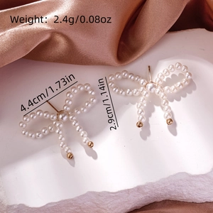 Detailed view of pearl bow earrings with size and weight specs on a silk background