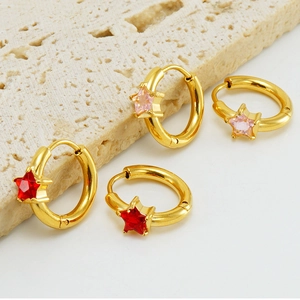 Close-up of gold-plated stainless steel star earrings with red and pink zircon inlay