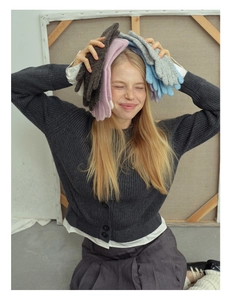 Various colors of thick wool blend knit gloves stacked on a model in an art studio