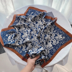 Elegant navy blue paisley silk scarf for women displayed on a white table