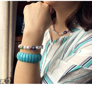 Close-up of bohemian turquoise beaded bracelet and floral glass bead necklace on a model