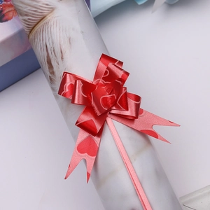 Macro shot of red pull bow with heart patterns for festive gift wrapping decoration