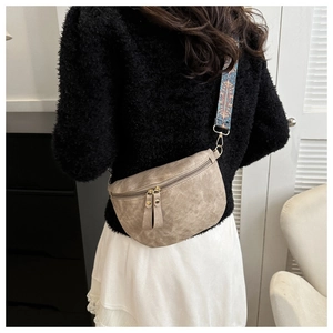Detail van kaki halve maan crossbodytas met bohemien geweven schouderband op een model