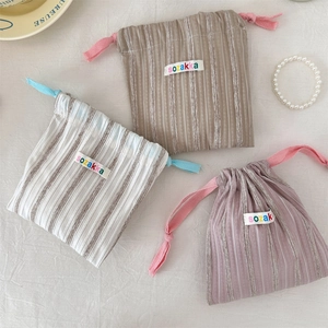 Detailed texture of vertical striped drawstring bags in earthy tones for cosmetics