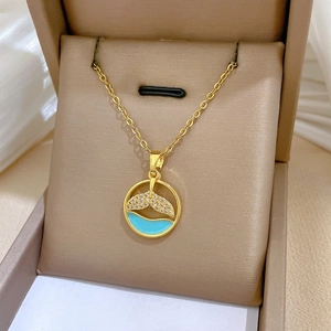 Detail of gold fish tail necklace with clear crystals and blue enamel in jewelry box