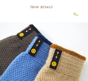 Close-up of knit wool texture and smile baby labels on colorful winter gloves