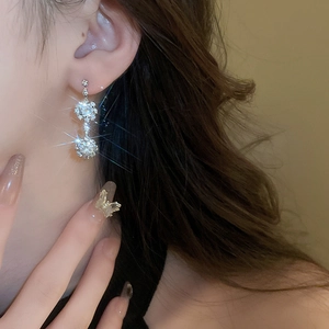 Detail of luxury silver butterfly ring and diamond earrings on model for women