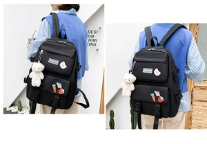 Detail showing black canvas backpack with bear plush charm and decorative pins on model