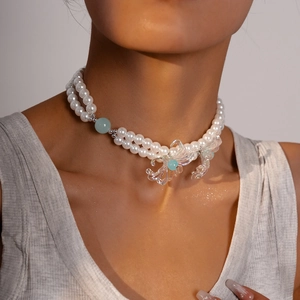 Close-up of double-layer faux pearl necklace with glass flower pendants on the neckline