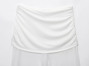 Detail of white two-layer fabric with elegant side ruching and textured knit patchwork