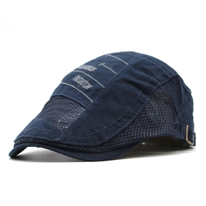 Detail of navy mesh beret featuring white fashion embroidery and bronze metal buckle