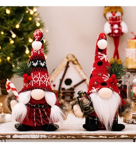 Close-up of Christmas gnomes with knit hats, holding a candy cane and lantern decorations