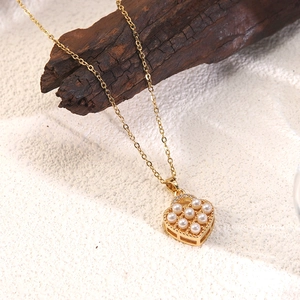 Detail of gold heart pendant with pearls and rhinestones on textured dark wood