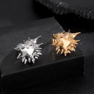 Detailed view of punk style gold and silver urchin spike rings on black jewelry display