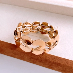 Detailed close-up of gold elastic S-shaped metal bracelet with textured brushed finish