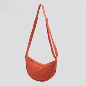 Detailed view of burnt orange crescent nylon bag with adjustable strap and top zipper