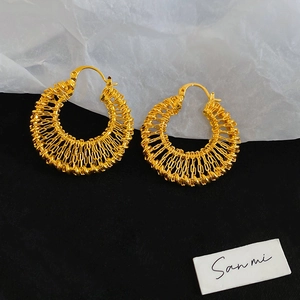 Macro shot of 18k gold plated woven hollow hoop earrings with classic clasp detail