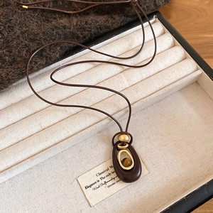 Makroaufnahme von Tigerauge-Anhänger mit Holzrahmen auf einer Geschenkbox