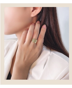 Detail of wide gold textured ring with hammered finish worn by a model in satin dress