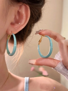 Close-up of model wearing light blue glazed C-shaped hoop earrings in minimalist style