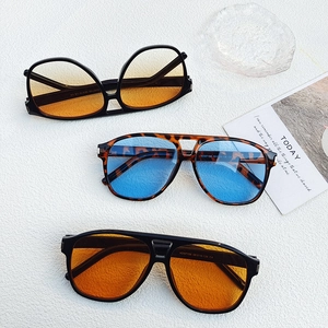 Detailed flat lay of three oversized pilot sunglasses in orange and blue lenses