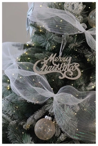 Detail of Merry Christmas sign with white mesh bow and golden glitter on xmas tree