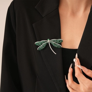 Detail of dragonfly brooch with emerald stones on a professional black blazer