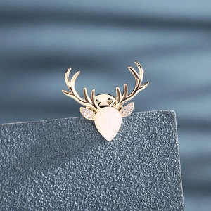 Macro shot of gold-plated deer head brooch with opal stone and sparkling zircon details